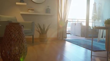 Sıcak güneş ışığı modern bir oturma odasını bej bir kanepe, parlak bir metal masa üzerindeki saksı bitkisi ve şık bir balkon manzarasıyla doldurur. Konforlu kentsel ortam kavramı