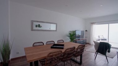 Ahşap bir masası, ahşap sandalyeleri ve cam bir sürgülü kapının doğal ışığıyla aydınlatılmış kapalı mekan bitkileri olan modern yemek odası. Minimalist ev dekorasyonu kavramı