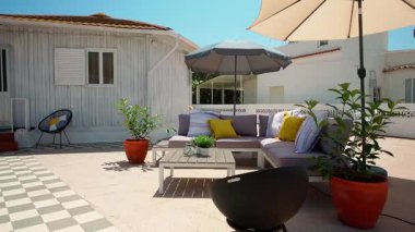 Siyah yuvarlak sehpası olan minimalist bir oturma odası, büyük bir televizyon ve açık hava avlusuna açılan kapalı bir bitki. Yumuşak doğal ışık boşluğu doldurur modern ev konforu ve iç tasarım kavramı