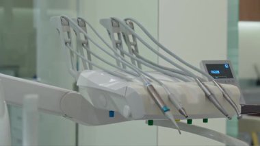 Modern bir klinikteki kontrol paneline bağlı ergonomik tasarımı ve esnek boruları olan diş tellerinin yakın çekimi.
