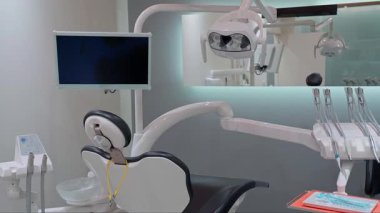 Temiz ve modern bir diş kliniğinde ayarlanabilir ışıklandırma, dijital monitör, enstrüman tepsisi ve ergonomik başlığı olan yüksek teknoloji diş muayenesi koltuğu.