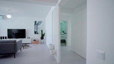 Çağdaş bir oturma odasında dekoratif yastıklı gri bir kanepe, zebra desenli bir halı, yuvarlak bir sehpa ve geniş pencereli kahverengi deri bir sandalye bulunur..