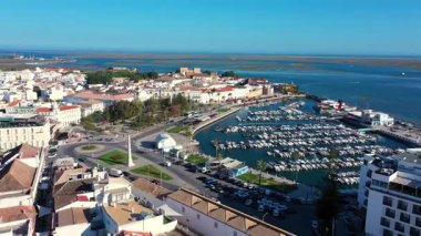 Portekiz 'in Faro şehrinin havadan görünüşü, tarihi şehir merkezini gözler önüne seriyor, tekneler, yeşil park alanları ve ufka uzanan Ria Formosa gölünün çarpıcı mavi suları ile dolu marina..