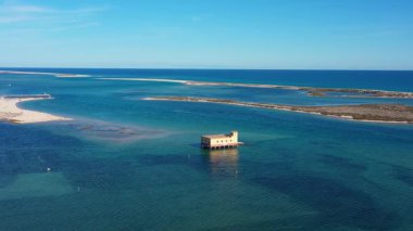 Fuseta Portekiz 'deki terk edilmiş cankurtaran botunun kristal berrak sular, kumsallar ve manzaralı bir kıyı lagünüyle çevrili nefes kesici bir görüntüsü.