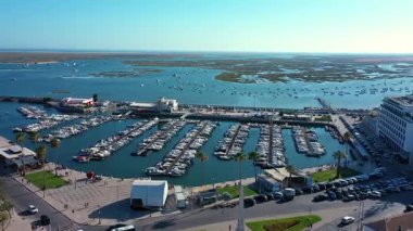 Portekiz 'deki Faro marinasının güzel bir hava manzarası, çok sayıda tekne, rıhtım gezisi, palmiye ağaçları ve ufka doğru uzanan geniş Ria Formosa gölünün yer aldığı..