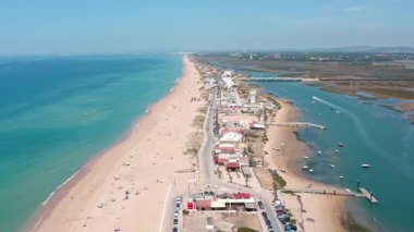 Güzel hava perspektifi Faro plajını, kumlu kıyılarını, kristal berrak turkuaz sularını ve Portekiz 'in Algarve Bölgesi' nde korunan bir doğal park olan huzurlu ria formosa lagününü gözler önüne seriyor.