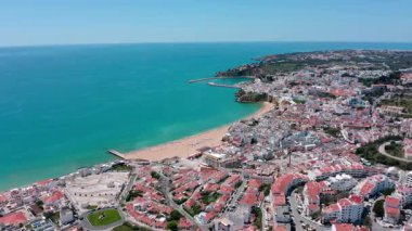 Albufeira panoramik manzarası canlı kıyı şeridini, kumlu plajları ve turkuaz okyanus sularını parlak yaz günlerinde manzaraya yayarak yakalıyor. Hava manzaralı praia dos pescadores.