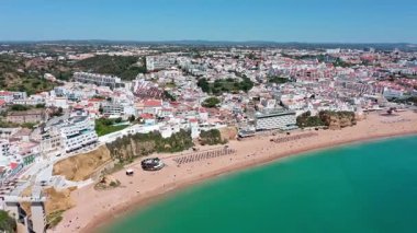 Albufeira şehri ve kıyı şeridi beyaz binaları, plajları, turkuaz suları ve Portekiz 'in algarv bölgesinde yaz tatilinin tadını çıkaran turistleri gösteriyor. Praia dos pescadores.