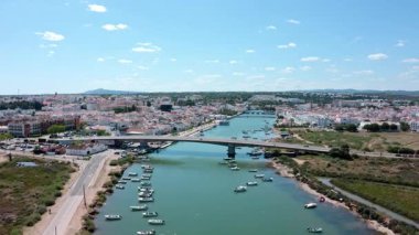 Çoklu hava perspektifleri, tavira, Portekiz 'den geçen Gilao nehrinin, açık mavi gökyüzü altında köprü, tekne ve çevre kentsel manzarayı vurguluyor.