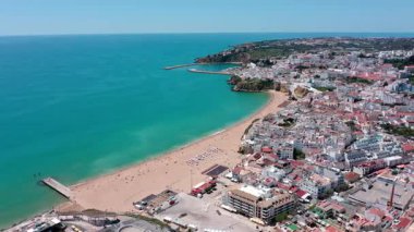 Albufeira şehri ve Algarve, Portekiz 'deki sahil, renkli binalar, turkuaz sular ve kumlu kıyılar, canlı bir kıyı manzarası yaratıyor. aerial Praia dos pescadores.