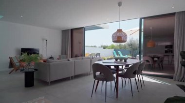 Çağdaş oturma odası doğal ışıkla yıkanmış, şık bir yemek alanı, rahat bir kanepe, ferahlatıcı havuzu ve dinlenme yerleri olan güneşli bir avlu var.