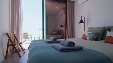 Lüks otel odası geniş okyanus manzarasını gözler önüne seriyor. Zarif bir oturma düzeni ve yumuşak doğal ışıklandırma ve sofistike tasarım elementleriyle sakin bir sahil atmosferi var.