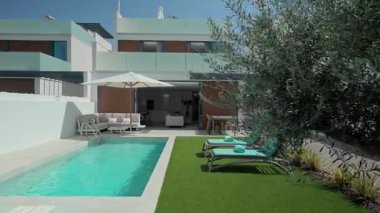 Güneş ışığı, turkuaz bir yüzme havuzu, güneşlik, güneşlik ve sentetik bir çimenlik içeren el değmemiş beyaz bir villayı aydınlatarak lüks ve rahatlatıcı bir atmosfer yaratıyor.