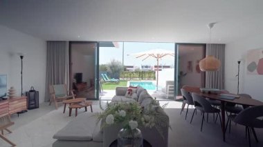 Günışığı modern mobilyalar ve yemyeşil yeşilliklerle dolu, pırıl pırıl bir havuzu ve terası olan açık bir vahaya kusursuz bir geçiş gösteren çağdaş bir oturma odasını aydınlatıyor.