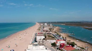 Faro, Portekiz yakınlarındaki kumlu bir sahil olan Praia de Faro 'nun hava manzarası. Turistler güneşli günün ve Ria formosa lagününün yanındaki Atlantik Okyanusu' nun mavi denizinin keyfini çıkarıyorlar.