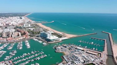 Yat ve teknelerle dolu Vilamouras neşe dolu marinası, havadan bakıldığında alg kıyı şeridinin güzelliğini gözler önüne seren çarpıcı kumlu bir sahile sınır çiziyor. Vilamoura Portekiz 15.06.2025
