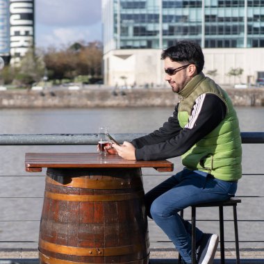 Nehir kenarındaki bir barda gülümseyen bir adam mesaj yolluyor.