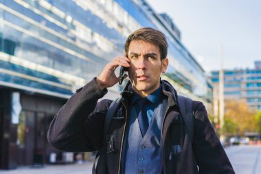 Ofisinin yakınında cep telefonuyla konuşan yakışıklı bir işadamı. Boşluğu kopyala