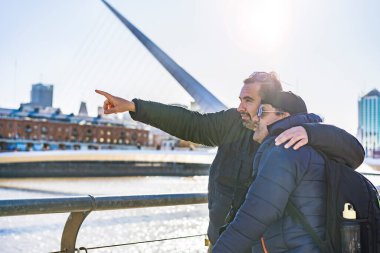 LGBT çifti dışarıda birbirlerine sarılıyorlar. Gezginler. Biri tarihi bir yeri işaret ediyor..
