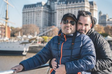 LGBT gay çifti kameraya bakarken birbirlerine sarılıyorlar..