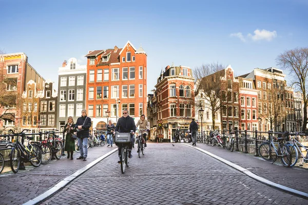 Amsterdam, Hollanda - 13 Mart 2023: Amsterdam eski kentinde insanlar bisiklet sürüyor ve su kanalında yürüyorlar