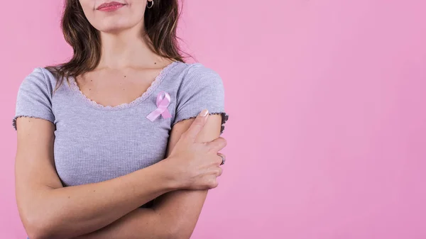 A pink badge ribbon on a woman's chest supporting breast cancer cause