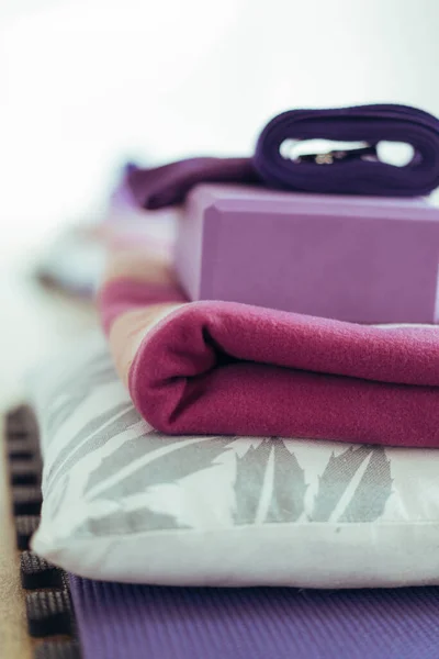 Close-up of yoga equipment: Yoga mat, block, strap, blanket and pillow