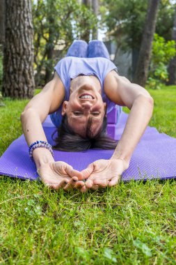 Kameraya bakarken yoga bloklarında uzanan mutlu, gülümseyen kadın. Dikey çekim.