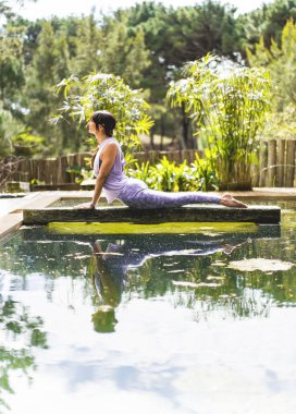 Yoga yapan, Kobra pozisyonunda uzanan bir kadın (Bhujangasana egzersizi) açık havada. Dikey çekim.