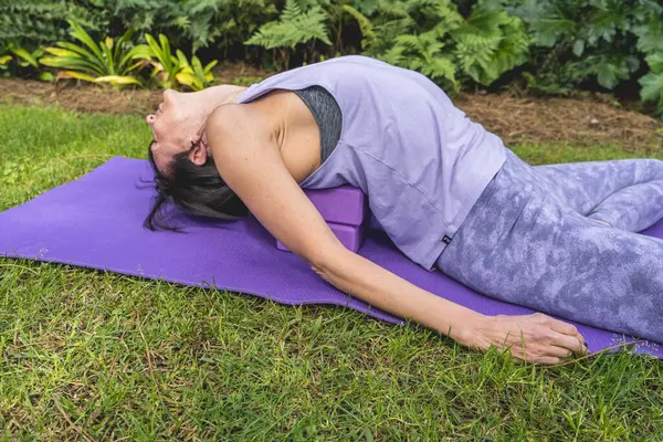 Woman lies on a yoga block to improving posture.