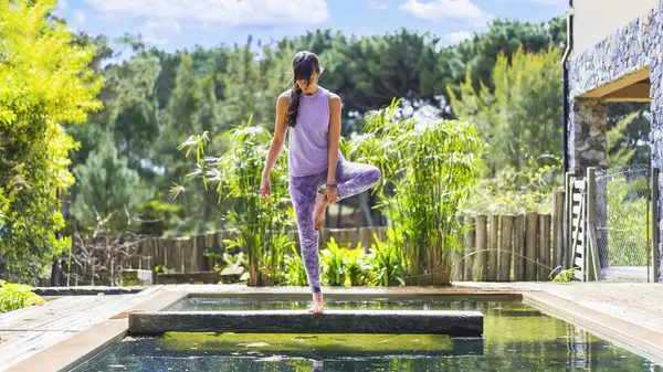 Yetişkin bir kadın havuzda yoga yapıyor..