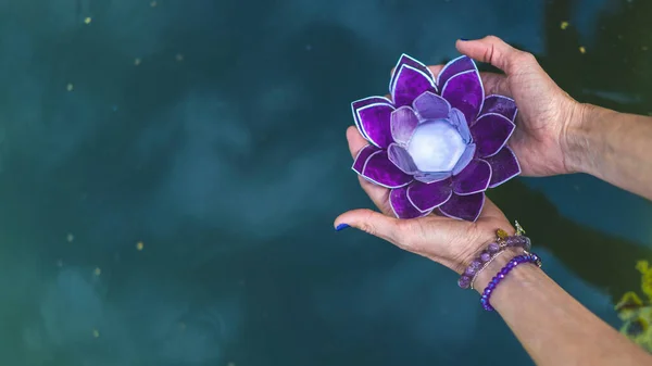 手拿着紫色玻璃莲花在水面上的顶角视图 瑜伽和冥想的概念 复制空间 — 图库照片