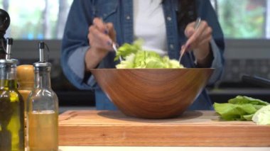 Sağlıklı salata bir kadın tarafından ahşap kaseye konuyor. 