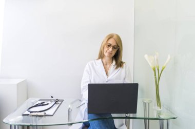 Tıp bürosunda dizüstü bilgisayarda çalışan kadın doktor..