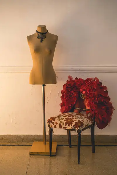 Red fashion coat hanging on a chair near an empty mannequin. Stylish and fashion concept