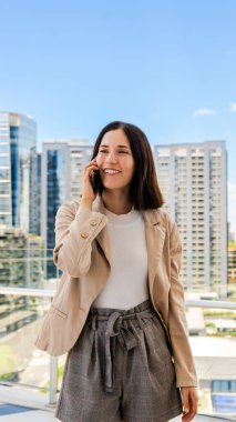 Gülümseyen bir bayan girişimci, akıllı telefonunu biriyle konuşmak için kullanıyor..