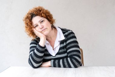 Kameraya bakan orta yaşlı kızıl saçlı bir kadının portresi.