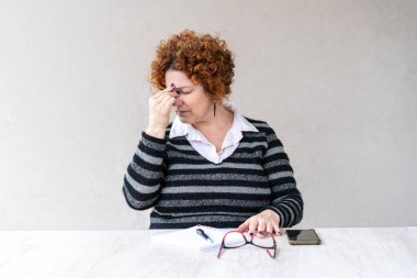 Orta yaşlı kızıl saçlı bir kadın baş ağrısı yüzünden çalışmayı bıraktı.