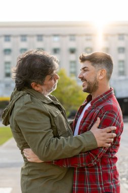 Birbirine aşık iki evli adam birbirine bakıyor ve sarılıyorlar. Dikey çekim