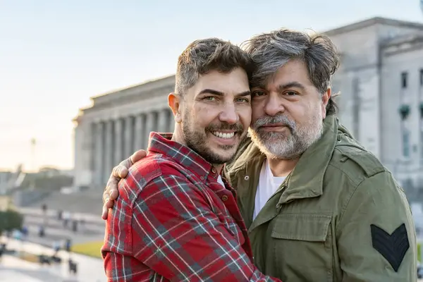 Yakın plan İspanyol eşcinsel çift Buenos Aires 'te kameraya bakarken sarılıyorlar..