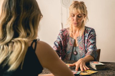 Tarot okuyucusu, kartlardaki mesajları meraklı müşterisine sevinçle açıklıyor.