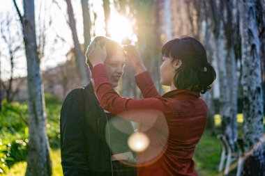 Genç bir kadın sevgilisinin kafasına sevgiyle bere takıyor.