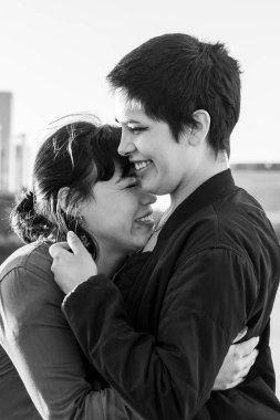 Black and white portrait of a couple of women embracing and laughing together clipart