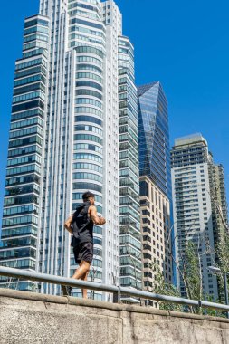 Etrafı gökdelenlerle çevrili, hareketli bir caddede koşan zinde bir genç..