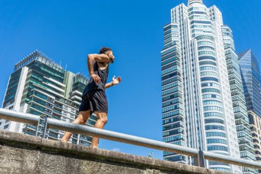 Genç adam şehrin kaldırımında ferahlatıcı bir koşuya çıkıyor..