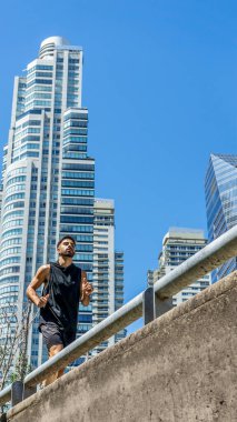 Yüksek binalarla dolu bir şehrin sokaklarında koşan şehir koşucusu..