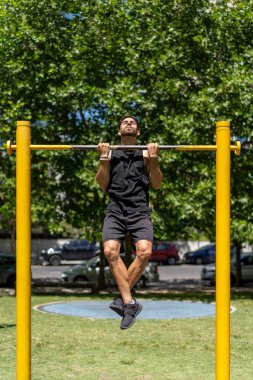 Park ortamında barfiks çeken zinde bir genç..