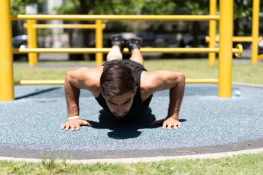 Formda erkek, açık hava spor salonunda şınav çekiyor..