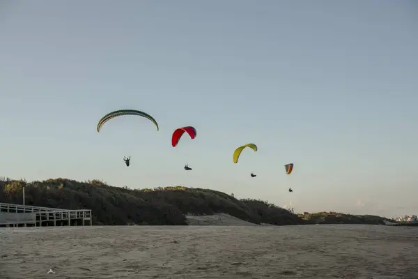 Paragliderler kum tepelerinin üzerinde zarif bir şekilde süzülüyorlar.