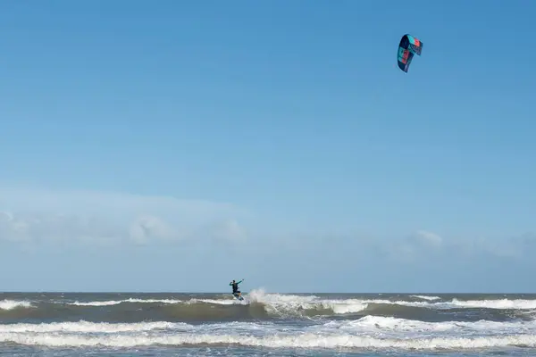 Parlak bir günde okyanus dalgaları üzerinde dinamik uçurtma sörfü